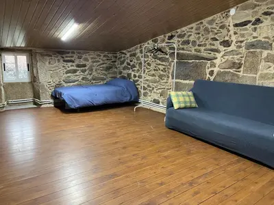a living room with a couch and a stone wall at Casa Xulián in Monterroso