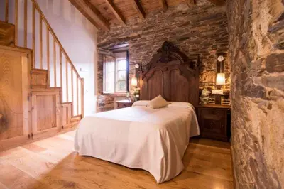 a bedroom with a large bed and a stone wall at CASA DE ALDEA VAL DOS SOÑOS in Lugo