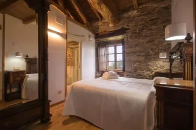a bedroom with a large bed with a stone wall at CASA DE ALDEA VAL DOS SOÑOS in Lugo