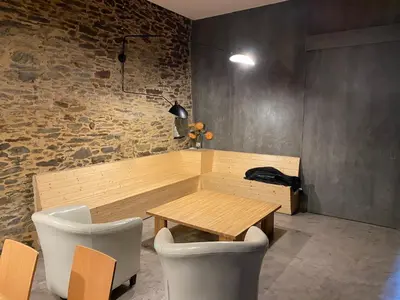a table and chairs in a room with a stone wall at Albergue O Santo in Arzúa