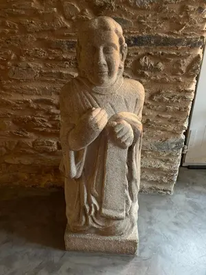 a statue of a man standing in front of a brick wall at Albergue O Santo in Arzúa