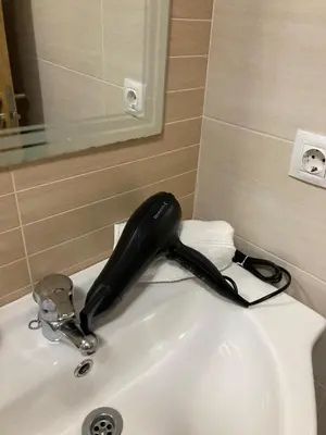a black hairdryer sitting on top of a sink at FOZ II PLAYAS in Foz