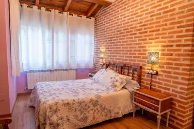 a bedroom with a bed and a brick wall at Casa del patio in Villanueva de Valdueza