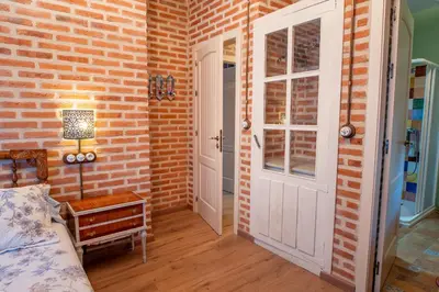 a bedroom with a brick wall and a door at Casa del patio in Villanueva de Valdueza