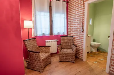 a room with two wicker chairs and a toilet at Casa del patio in Villanueva de Valdueza