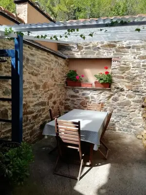 a table and chairs in a patio with a stone wall at Casa del patio in Villanueva de Valdueza