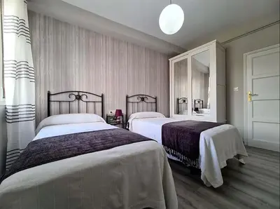 a bedroom with two beds and a mirror at Piso Estacion Tren Bus Termas muy luminoso in Ourense