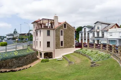 a house on a hill next to a stone wall at Ático tipo loft en San Sadurniño. in Santa María La Mayor del Rosario