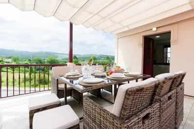 a dining room with a table and chairs on a balcony at Ático tipo loft en San Sadurniño. in Santa María La Mayor del Rosario