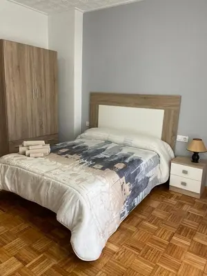 a bedroom with a large bed and a wooden floor at Coqueto alojamiento cercano a las termas A in Ourense