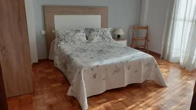 a bedroom with a bed and a wooden floor at Coqueto alojamiento cercano a las termas A in Ourense