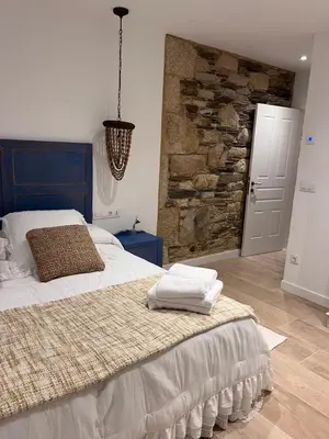 a bedroom with a large bed and a stone wall at Caraxolas in Lugo