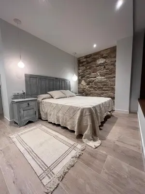 a bedroom with a large bed and a stone wall at Caraxolas in Lugo