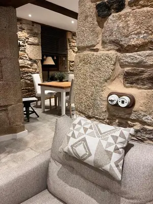 a living room with a couch and a stone wall at Caraxolas in Lugo