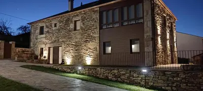 a stone building with lights on the side of it at Caraxolas in Lugo