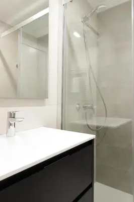 a white bathroom with a shower and a sink at Apartamentos Nature in Cangas del Narcea