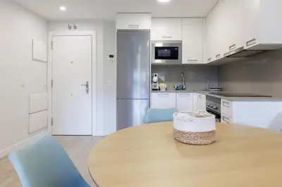 a kitchen with a wooden table and blue chairs at Apartamentos Nature in Cangas del Narcea