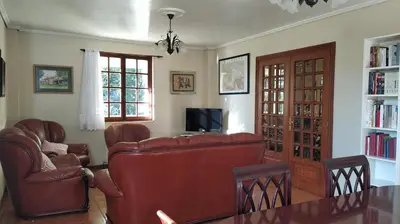 a living room with a couch and chairs and a television at Casa con jardín en la playa de Almieiras in Fene