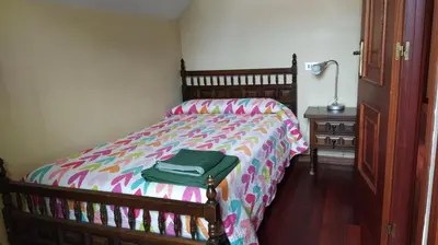 a bedroom with a bed with a green bag on it at Casa con jardín en la playa de Almieiras in Fene
