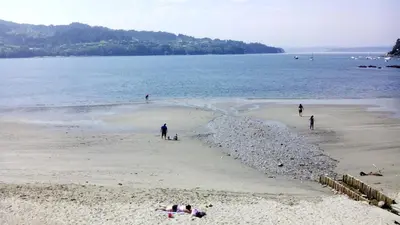 a group of people on a beach near the water at Casa con jardín en la playa de Almieiras in Fene