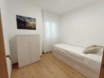a white bedroom with a bed and a cabinet at Duerming Ría de Viveiro in Viveiro