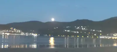 a moon rising over a body of water at night at Quintana&lev in Viveiro
