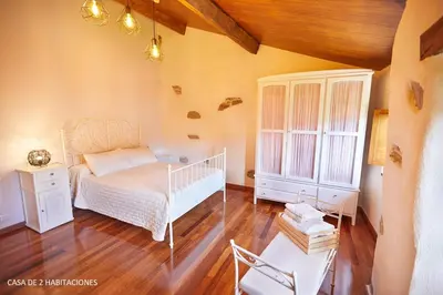 a bedroom with a white bed and a chair at Viveiro Río Pedroso in Vivero