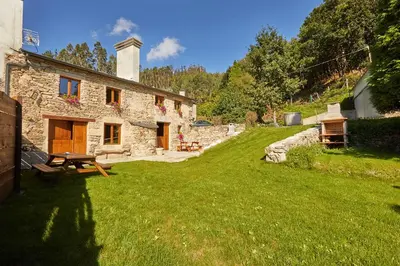 a stone house with a picnic table in a yard at Viveiro Río Pedroso in Vivero