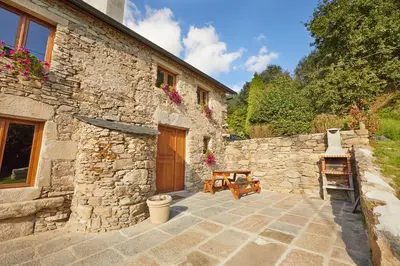 a stone house with a patio and a wooden door at Viveiro Río Pedroso in Vivero