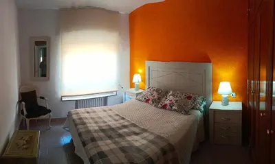a bedroom with orange walls and a bed and a window at Tu Apartamento Ideal in Ponferrada
