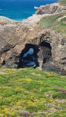 a rock cliff with two tunnels in the grass at Casiña de Érika in San Cosme de Barreiros
