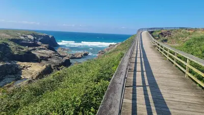 a train track on a wooden bridge over the ocean at Casiña de Érika in San Cosme de Barreiros