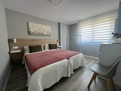 a bedroom with a large bed and a chair at Apartamento da Fraga in Arzúa