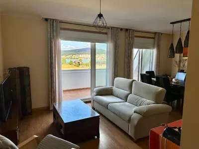 a living room with a couch and a glass door at Ático con vistas a la ría y a Foz in Barreiros