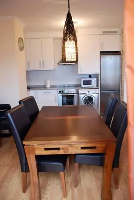 a kitchen with a wooden table and black chairs at Ático con vistas a la ría y a Foz in Barreiros