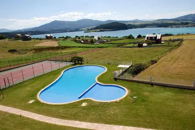 an empty swimming pool in a field with a lake at Ático con vistas a la ría y a Foz in Barreiros
