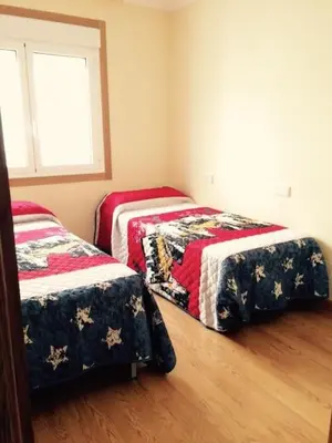 two beds in a room with a window at Ático con vistas a la ría y a Foz in Barreiros