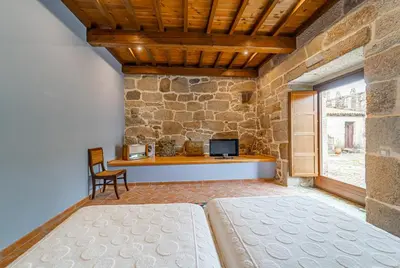 a bedroom with a bed and a tv in a stone wall at Casa Rural Pazo San Damian in Amoeiro