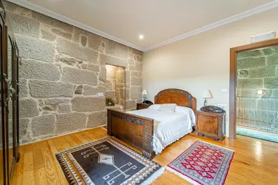 a bedroom with a bed and a stone wall at Casa Rural Pazo San Damian in Amoeiro