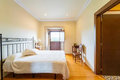 a bedroom with a bed and a table and a window at Casa Rural Pazo San Damian in Amoeiro
