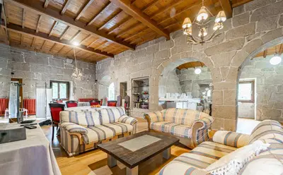 a living room with couches and a stone wall at Casa Rural Pazo San Damian in Amoeiro