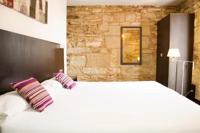 a bedroom with a large white bed with two pillows at Hotel A Tafona do Peregrino in Santiago de Compostela