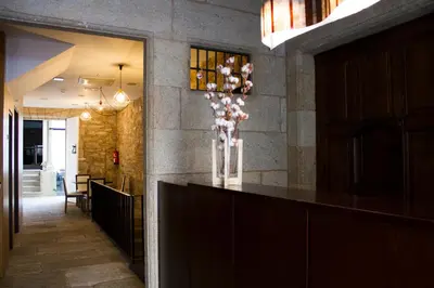 a lobby with a bar with a vase of flowers at Hotel A Tafona do Peregrino in Santiago de Compostela