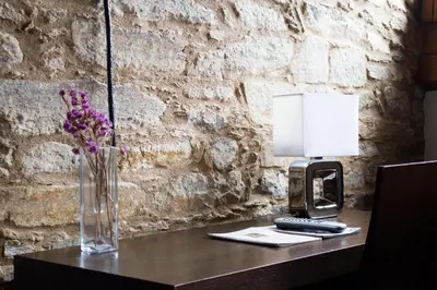 a table with a vase of flowers and a phone at Hotel A Tafona do Peregrino in Santiago de Compostela