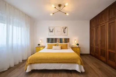 a bedroom with a large bed and a chandelier at Apartamento Alecrin Padrón in Padrón