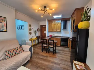 a living room and kitchen with a couch and a table at Apartamento Alecrin Padrón in Padrón
