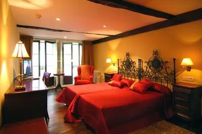 a bedroom with a large red bed with a red blanket at Hostal Santo Grial in Santiago de Compostela