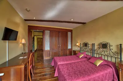 a bedroom with a large bed with pink sheets at Hostal Santo Grial in Santiago de Compostela