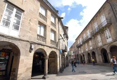 a group of people walking down a street next to buildings at Hostal Santo Grial in Santiago de Compostela
