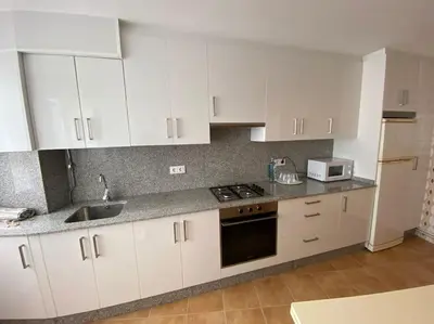 a kitchen with white cabinets and a sink at Río, mar y montaña in Puentedeume